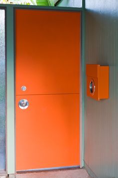 an orange door in front of a metal wall