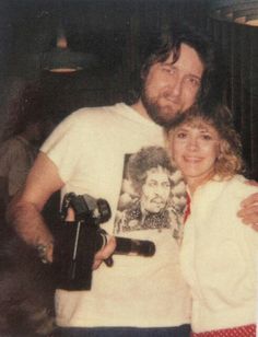 a man and woman standing next to each other in front of a mirror holding a camera