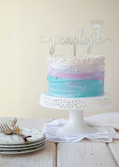 a cake sitting on top of a wooden table next to plates and silverware in front of a white wall