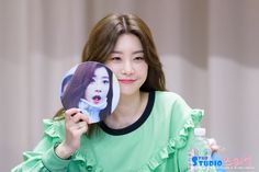 a woman holding up a fan with an image of herself on it in front of her face