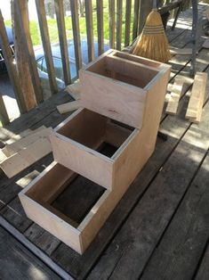 a wooden box sitting on top of a wooden deck next to a broom and chair