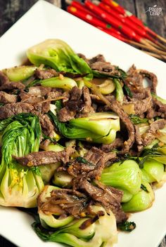 beef and broccoli stir fry on a white plate with chopsticks in the background