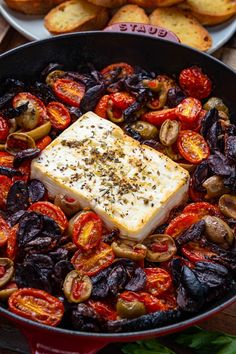 a pan filled with food next to some bread