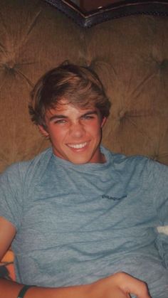 a young man sitting on top of a brown couch