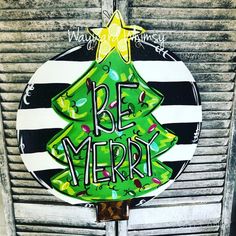 a green christmas tree painted on the side of a building with words be merry in black and white