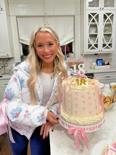 a woman standing in front of a cake on top of a white table with pink bows