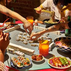 a group of people sitting around a table with sushi and chopsticks on it