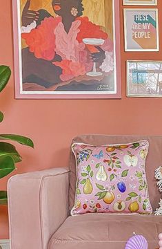 a living room with pink walls and pictures on the wall, including seashells