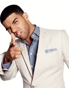 a man in a white suit pointing his finger at the camera while wearing a blue and white striped shirt