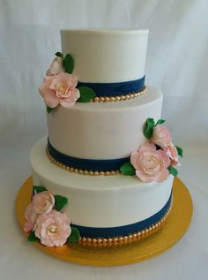 a three tiered cake with pink flowers on the top and blue trimmings