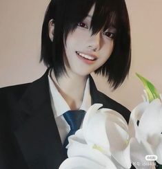 a man in a suit and tie with flowers on his lapel holding a white flower