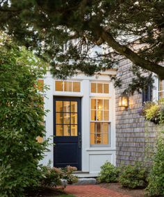 a blue door is in front of a gray house with white trim and brick walkway