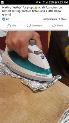 a person ironing something on top of a piece of tin foil with a green and white electric iron