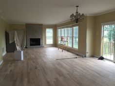 an empty living room with hard wood flooring and large windows in the back wall