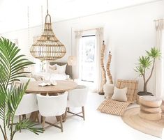 a living room filled with white furniture and lots of plants on the table in front of it