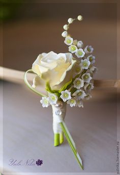 a white rose and baby's breath boutonniere bouquet on a table