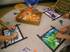 four children are sitting around a table making art with colored paper and scissors on it