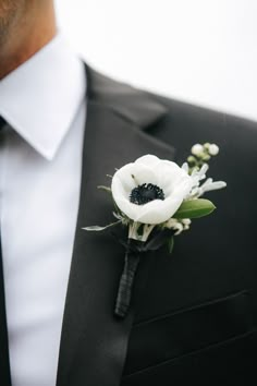 a man wearing a black suit and white flower boutonniere