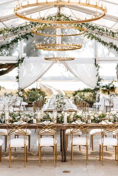 a table with white chairs and greenery is set up for an outdoor wedding reception