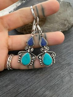 The perfect everyday light and comfy earrings with a unique double teardrop ethnic design. Made with alloy metal and a choice of 3 different mix of stones. They are made with Turquoise stone dust, Lapis stone dust and Coral stone dust, put together with resin. All have silver hooks. In one of the pictures you will see a number that represents the style for you to choose from. The earrings are 3.7cm- 1.30 inch long 1.7cm- 0.75 inch wide The drop length is 5cm- 2 inch. A unique addition to your ea Tibetan Ring, Wiccan Necklace, Mens Gemstone Rings, Earrings Aesthetic, Coral Stone, Skull Necklace, Ancient Jewelry, Thumb Rings, Turquoise Earrings