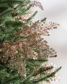 the branches of a pine tree are covered in gold and white glitter