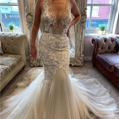 a woman in a wedding dress standing next to a couch and looking at the camera