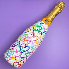 the bottle is decorated with multicolored letters and gold trim on it's side