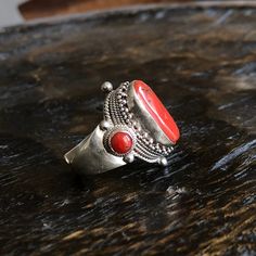 Red coral set on traditional Tibetan saddle Ring - Center coral measures approximately;  21mm X 12mm Smaller corals on the sides measures approximately 6mm Height of the ring is approximately 29mm , width  27mm Adjustable size fits sizes  9 to 10 1/2 It weights approximately 18 grams Handmade Artisan Red Rings, Traditional Red Ruby Ring, Artisan Red Ring Jewelry, Traditional Oval Red Ring, Traditional Red Oval Jewelry, Traditional Red Carnelian Ring, Traditional Oval Carnelian Rings, Red Oval Bohemian Rings, Red Coral Ring