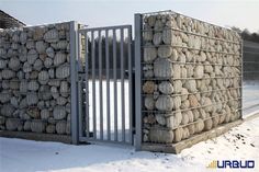 there is a large pile of rocks behind a gated in area with snow on the ground