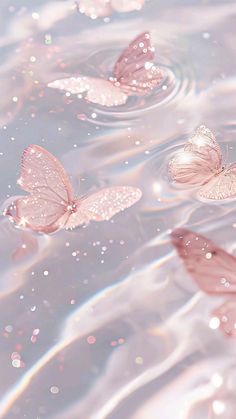 three pink butterflies floating in water with bubbles on the bottom and one flying above them