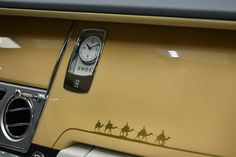 a car door with a clock on it and some people riding camels in the background