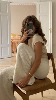 a pregnant woman sitting in a chair taking a selfie