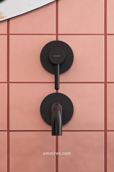 two black handles on a pink tiled wall