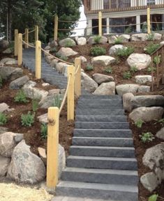 a set of stairs leading up to a house with rocks on the ground and trees in the background