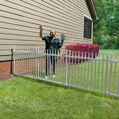 a man standing next to a white fence