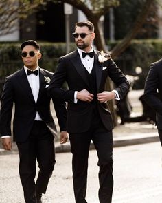 two men in tuxedos are walking down the street wearing sunglasses and bow ties