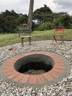 two chairs sitting next to a fire pit in the middle of a gravel covered field