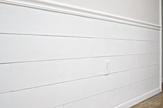 an empty room with white painted walls and wood flooring on the side of the wall