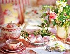 a table topped with plates and cups filled with food next to flowers on top of a table