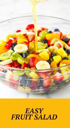 a glass bowl filled with fruit salad being drizzled over it's top