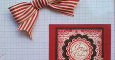 a red and white striped bow on top of a card with the letter m in it