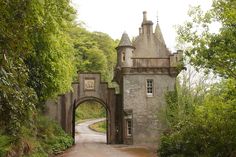 an old stone building with a gate in the middle of it surrounded by trees and bushes