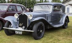 an old car is parked on the grass