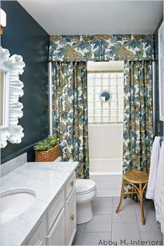 the bathroom is decorated in blue and white with flowers on the shower curtain, toilet, sink, and mirror