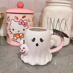 two hello kitty mugs sitting on top of a counter