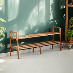 a wooden bench sitting in front of a green wall next to a potted plant