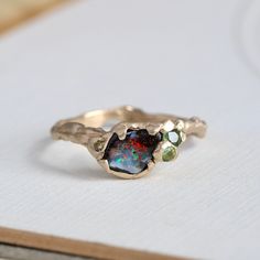 Our handmade 14k yellow gold boulder-opal ring celebrates the natural beauty of this fascinating gemstone, a unique specimen with vibrant flashes of firey orange, red, lime and electric turquoise blue. Accents of green sapphire, tourmaline, and champagne diamonds play to the sparks of bright color, with a gracefully undulating branch band and hand-hammered texture to emphasize the opal's slightly rustic nature. Shown in the last photo stacked with our custom made Willow band, which is sold separ Tourmaline And Opal Ring, Antique Opal Ring, Gemstone Rings Unique, Freeform Ring, Raw Opal Ring, Gemstone Stacking Ring, Boulder Opal Ring, Handmade Wedding Rings, Red Ring