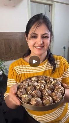 a woman holding a bowl filled with chocolate covered donuts