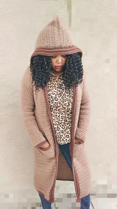 a woman standing in front of a white wall wearing a leopard print shirt and pink cardigan