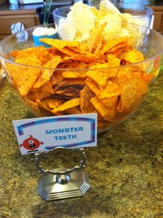 a bowl filled with tortilla chips on top of a counter next to a sign that says monster teeth